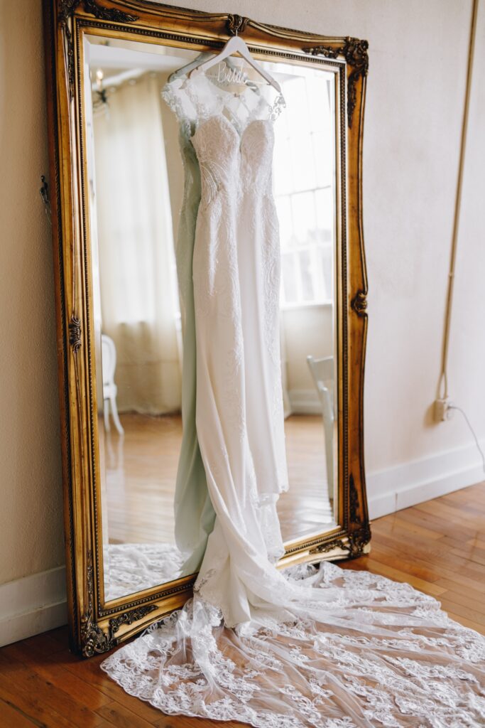 bridal gown hanging on large gold mirror