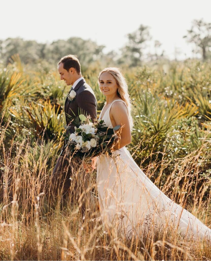 bride and groom walking through field