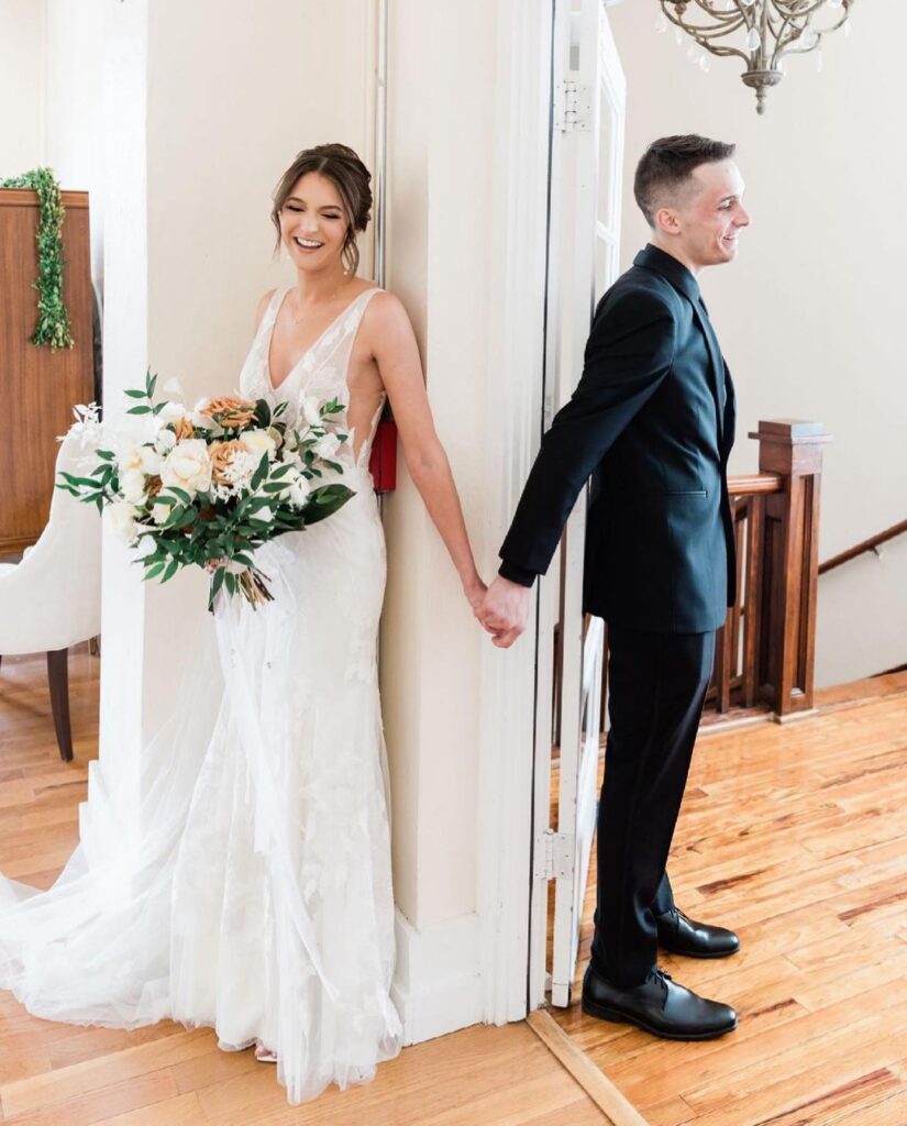 bride and groom holding hands around door before wedding