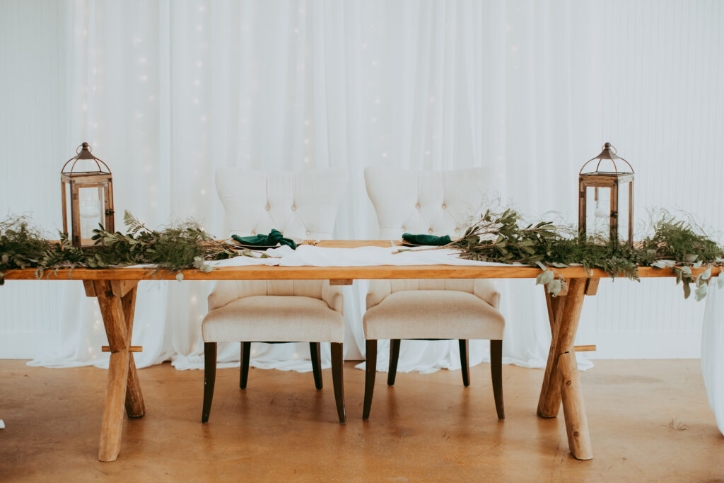 simple wooden table with greenery for bride and groom at wedding reception