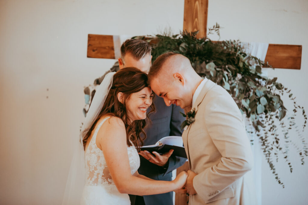 bride and groom holding hands and laughing during wedding ceremony